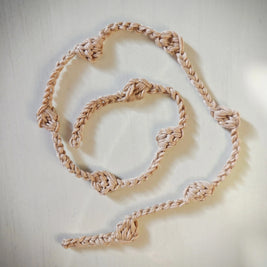 Handmade crochet cord with knots in natural yarn on a light surface, cozy gift decor
