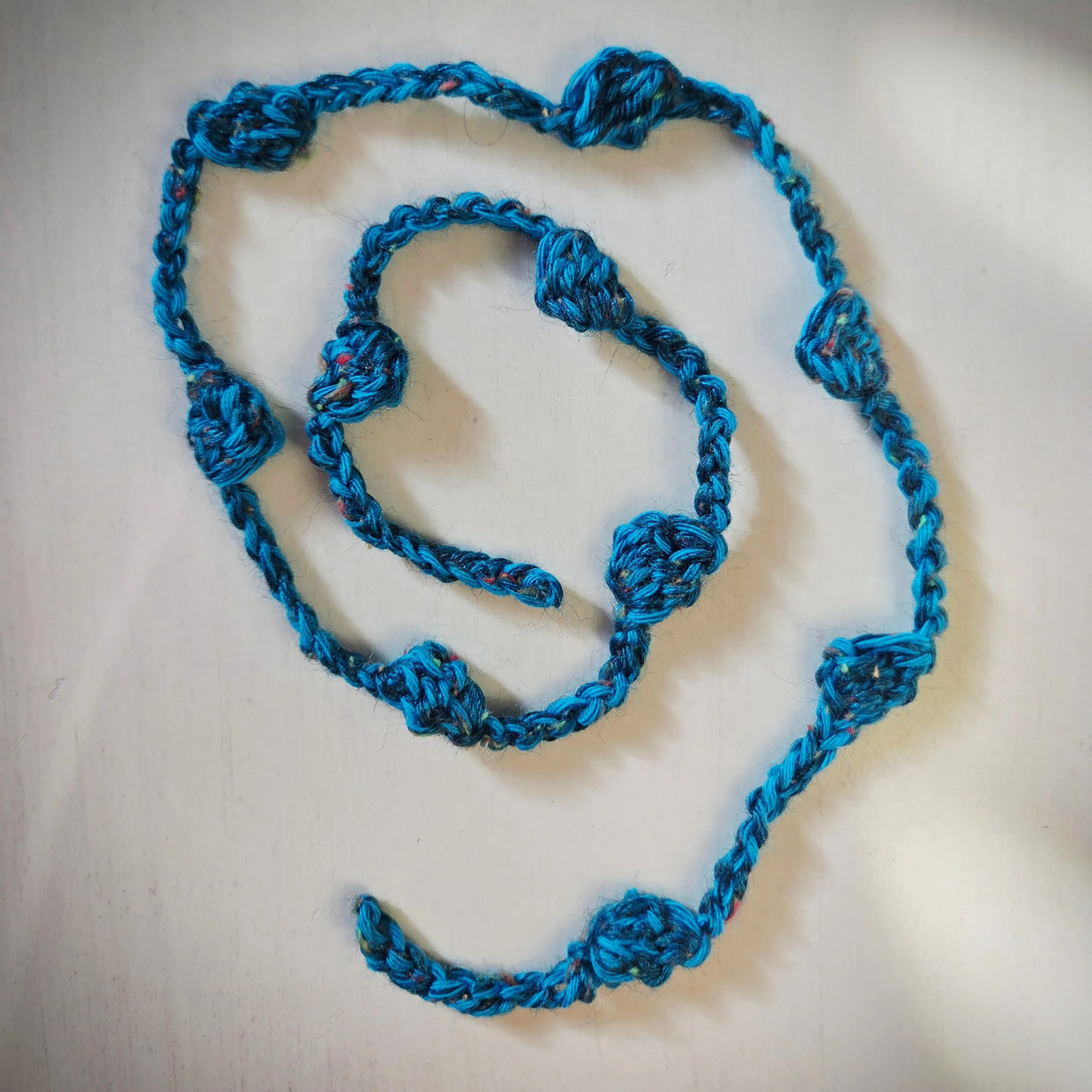 Handmade blue crochet garland with textured knots on white surface, Erika Liesel gift