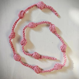 Handmade pink crochet garland with textured knots on a white surface