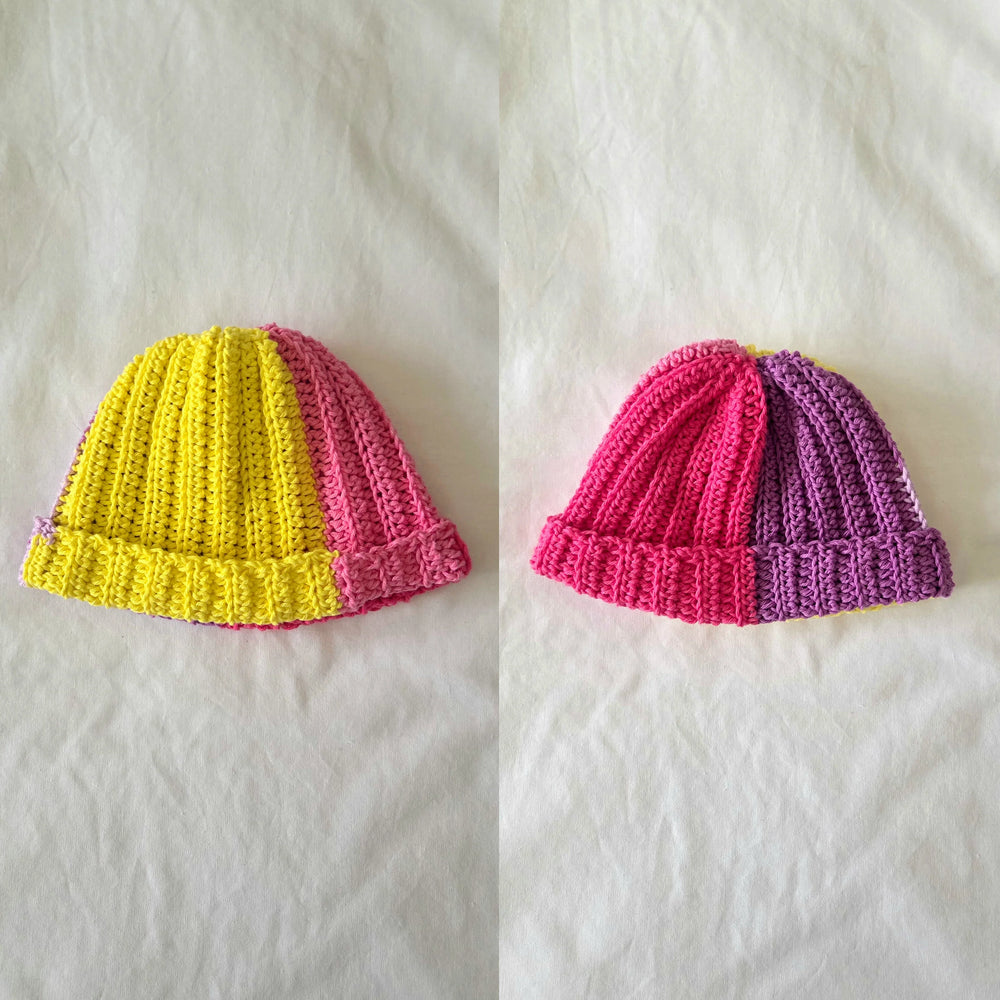 Handmade crochet beanie in vibrant yellow-pink and pink-purple color blocks, cozy and stylish winter hat.