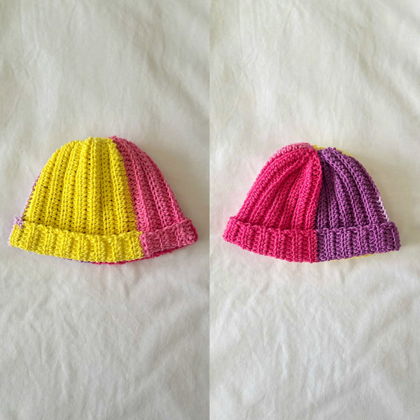 Handmade crochet beanie in vibrant yellow-pink and pink-purple color blocks, cozy and textured for everyday wear.
