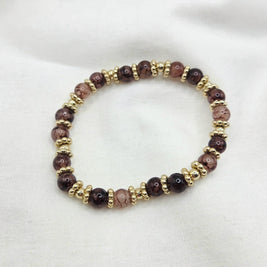 Handmade beaded bracelet with brown marbled and gold beads on white fabric
