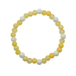 A beaded stretch bracelet made of alternating translucent pale yellow and opaque white round beads, displayed on a plain light background.