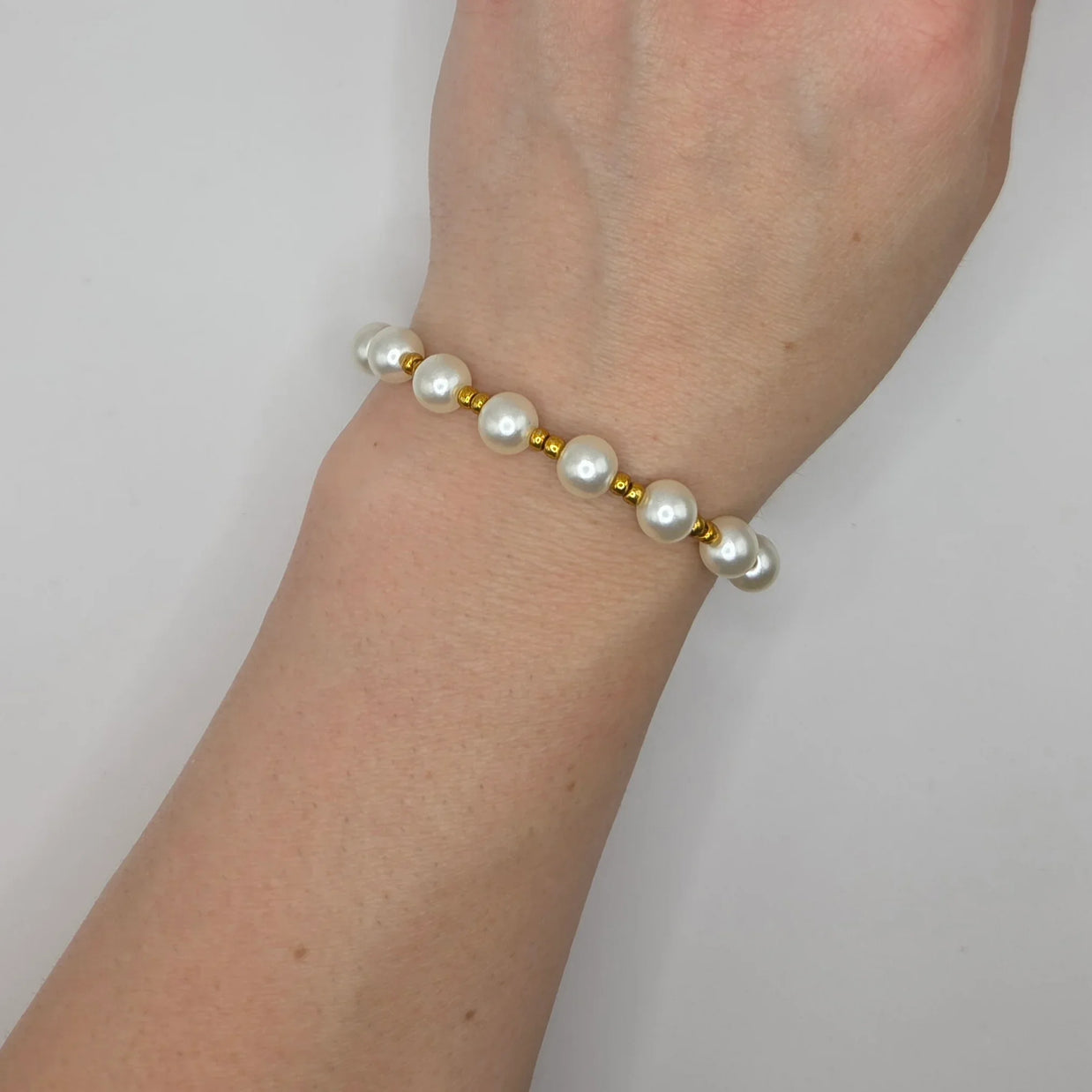 Elegant pearl and gold bead bracelet worn on wrist, perfect handmade gift for everyday elegance.