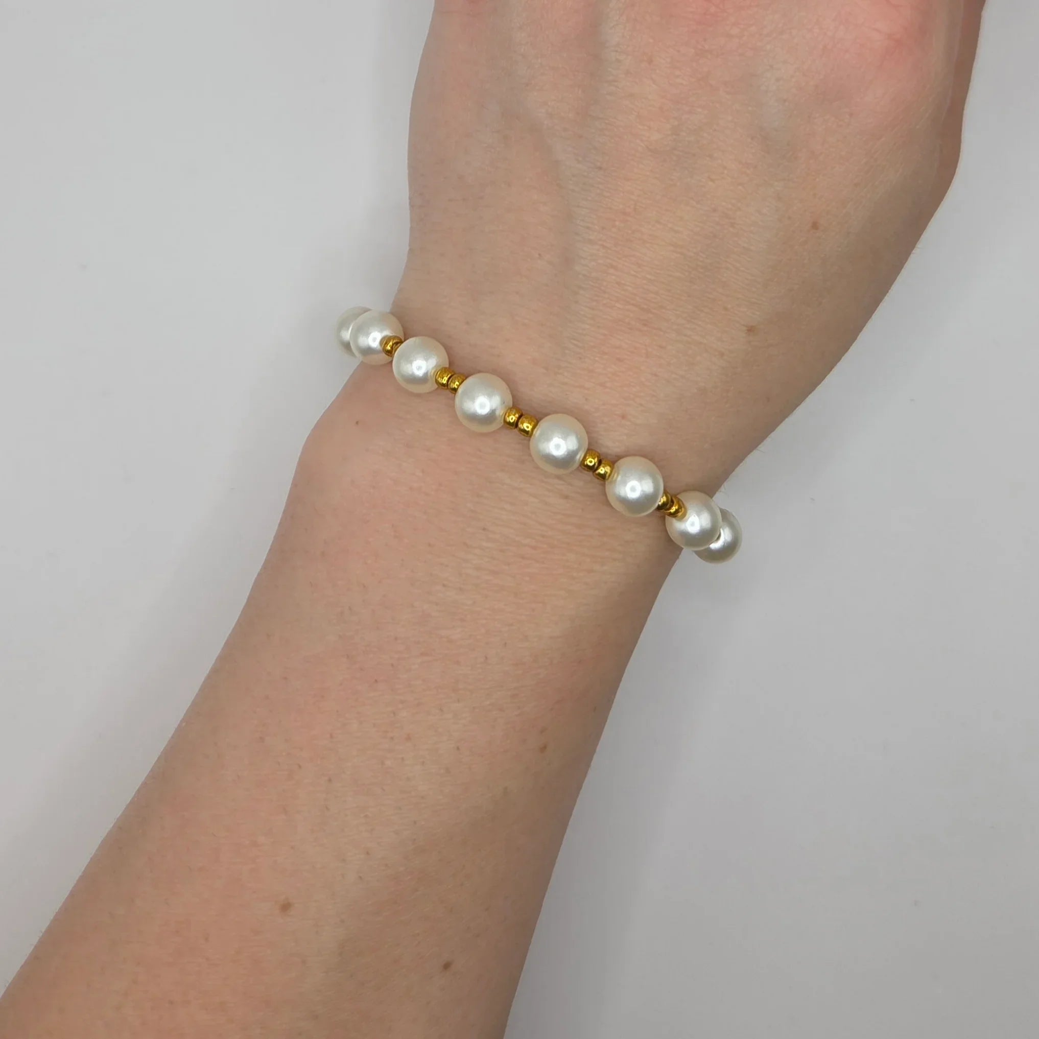 Elegant pearl and gold bead bracelet worn on wrist, perfect handmade gift for everyday elegance.