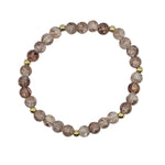 A beaded stretch bracelet made of faceted round beads in a dusty rose and brown color, with small metallic gold spacer beads, displayed on a light gray background.