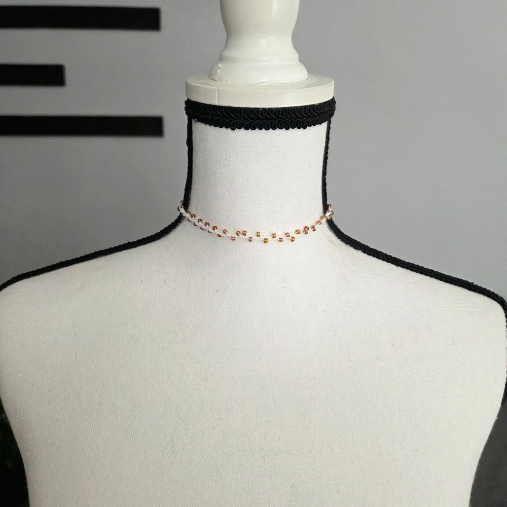 Handmade beaded choker necklace with gold beads on white mannequin, cozy crochet accessory