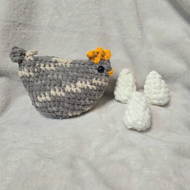 Handmade crochet chicken with yellow comb and white eggs on soft blanket