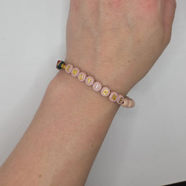 Pink beaded bracelet spelling 'EMOTIONS' with gold letters, worn on wrist