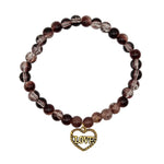 A beaded stretch bracelet featuring round dark brown and translucent clear beads, with a gold heart-shaped charm engraved with the word 'LOVE', displayed on a light off-white background.