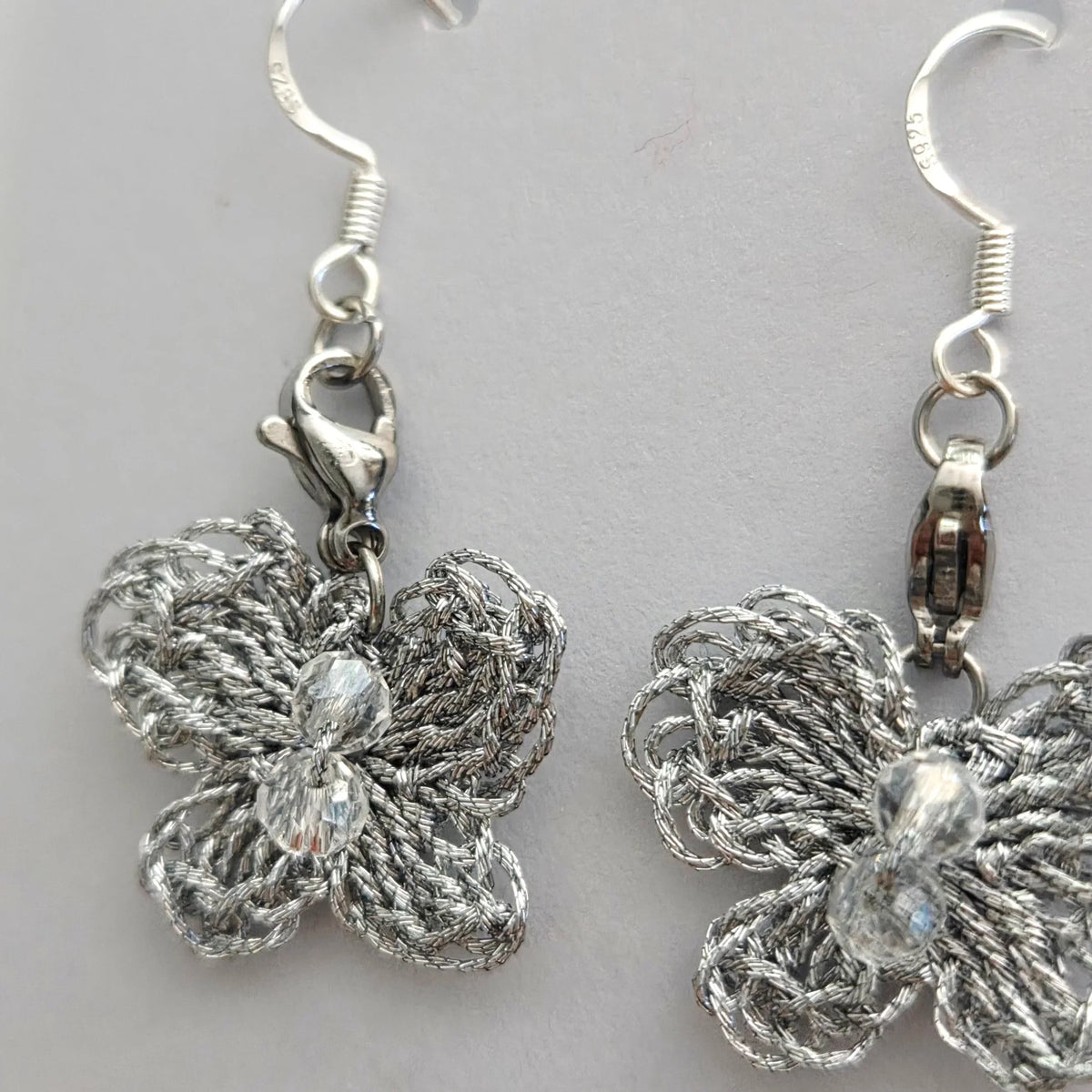 Handmade by Erika Liesel silver crochet butterfly drop earrings with crystal bead accents and sterling silver wires.