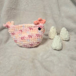Handmade crochet chicken with pastel pink and white yarn, cozy plush texture, perfect for Easter or baby gifts.