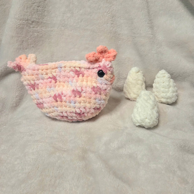 Handmade crochet chicken with pastel pink and white eggs on soft blanket