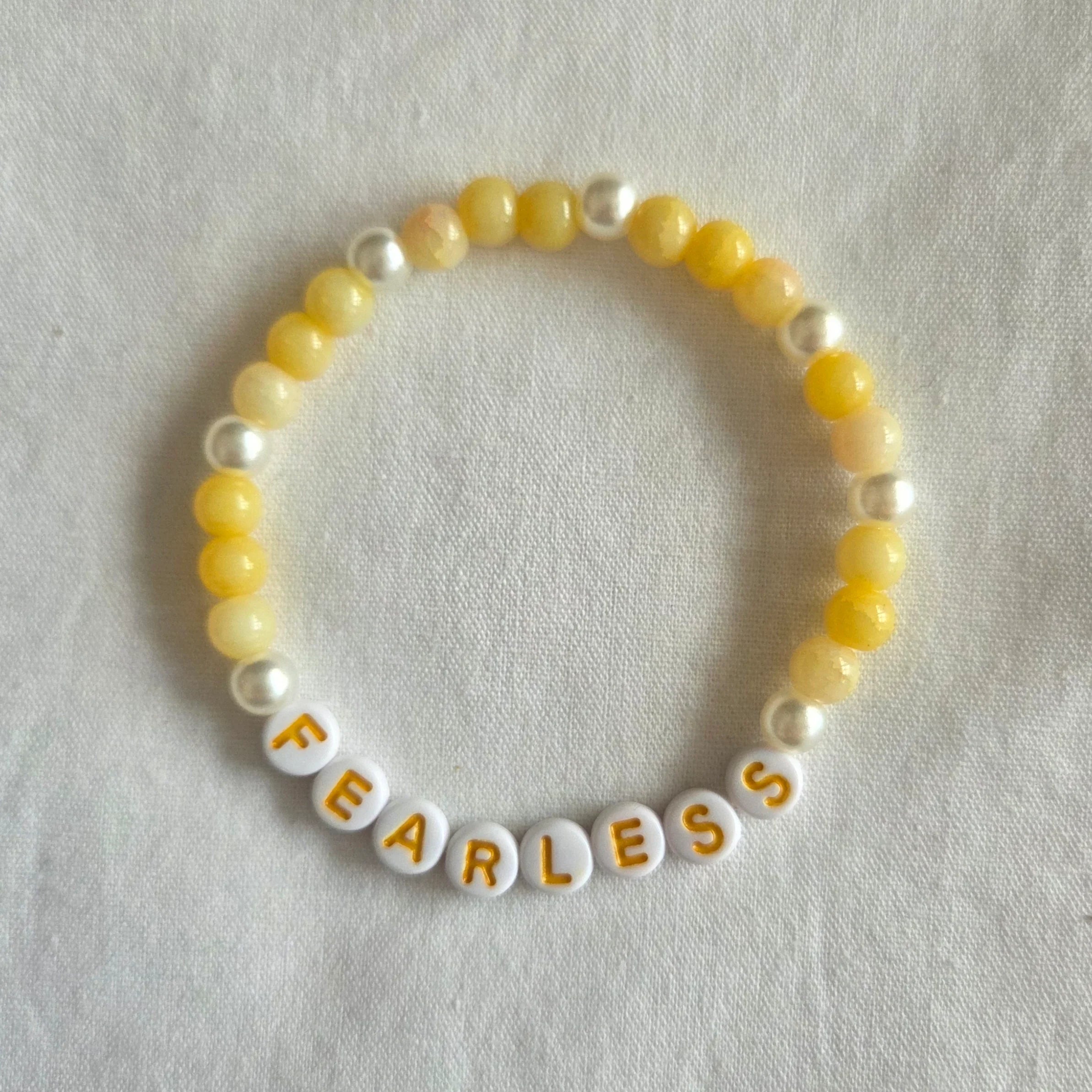 Yellow and white beaded bracelet with 'FEARLESS' letter beads, handmade for cozy, creative style