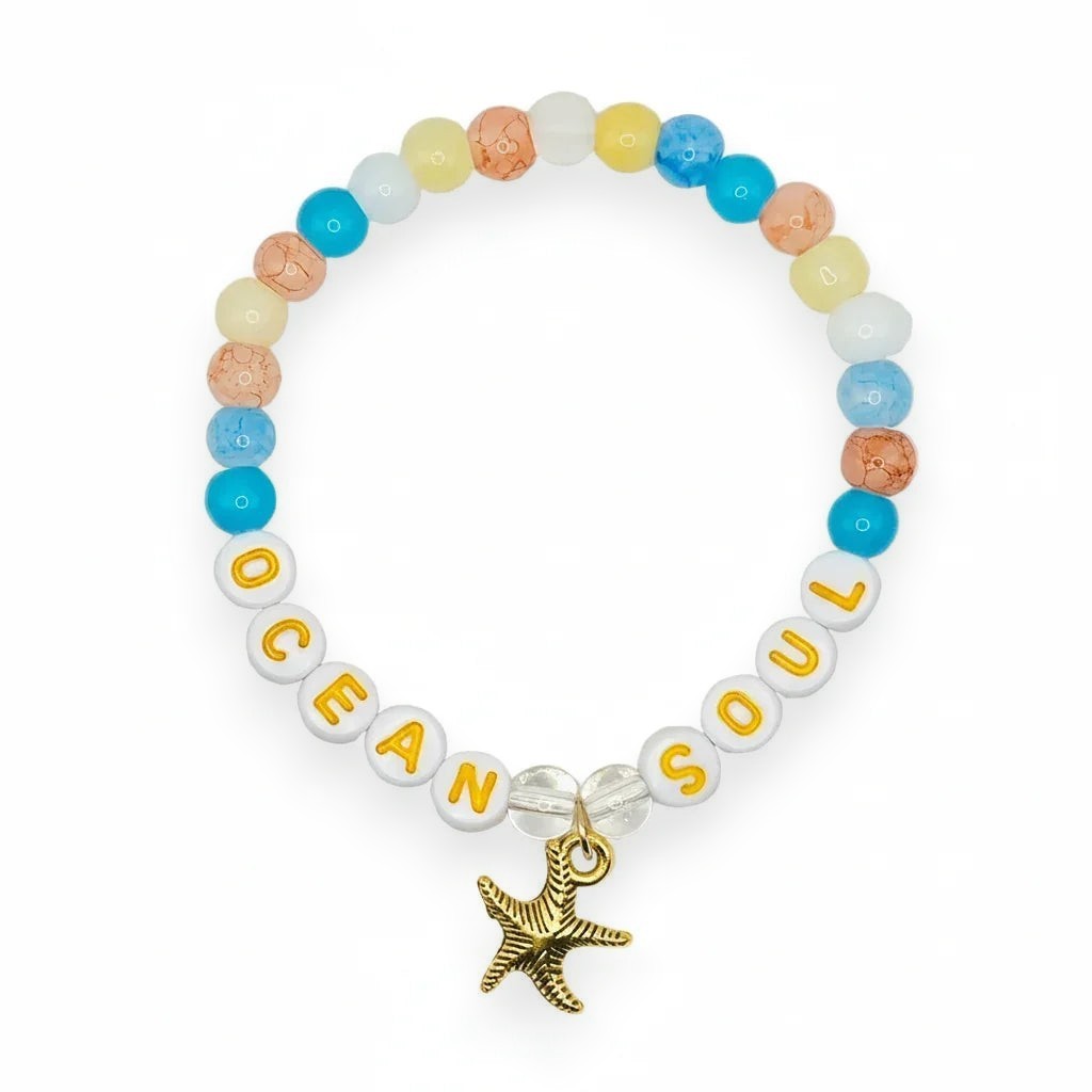 A beaded stretch bracelet spelling 'OCEAN SOUL' with a gold starfish charm, displayed on a light gray background.