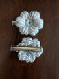 Handmade crochet flower hair clips with metal clasps on a dark wooden surface