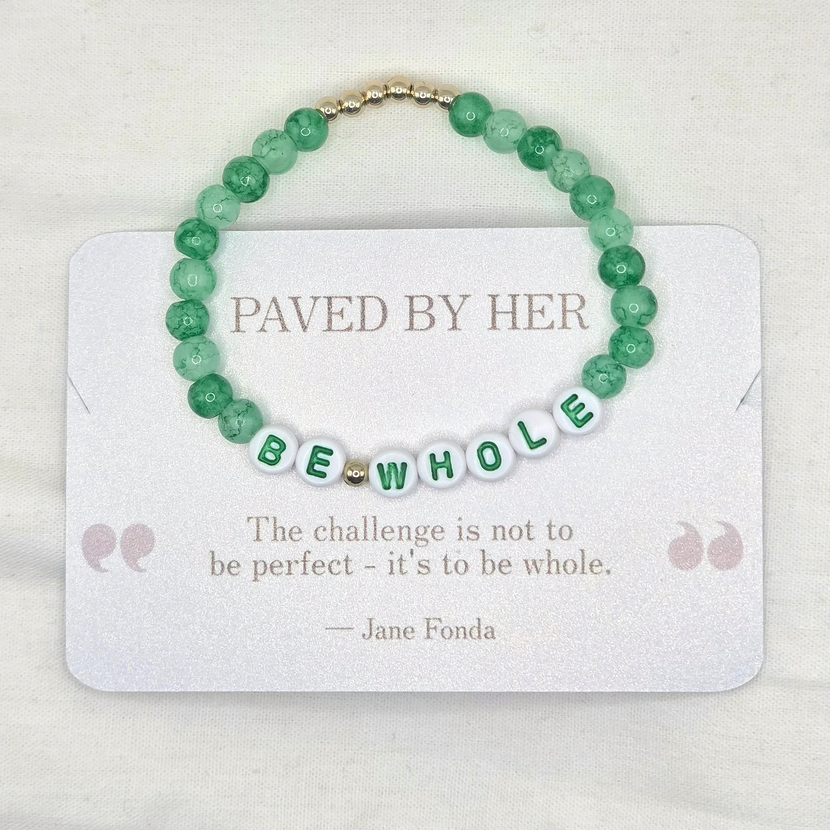 Green beaded bracelet with 'BE WHOLE' letter beads, displayed on a card with inspirational quote.