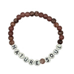 A beaded stretch bracelet on a light gray background, featuring marbled brown and reddish-brown beads with white letter beads spelling 'NATURE SOUL'.