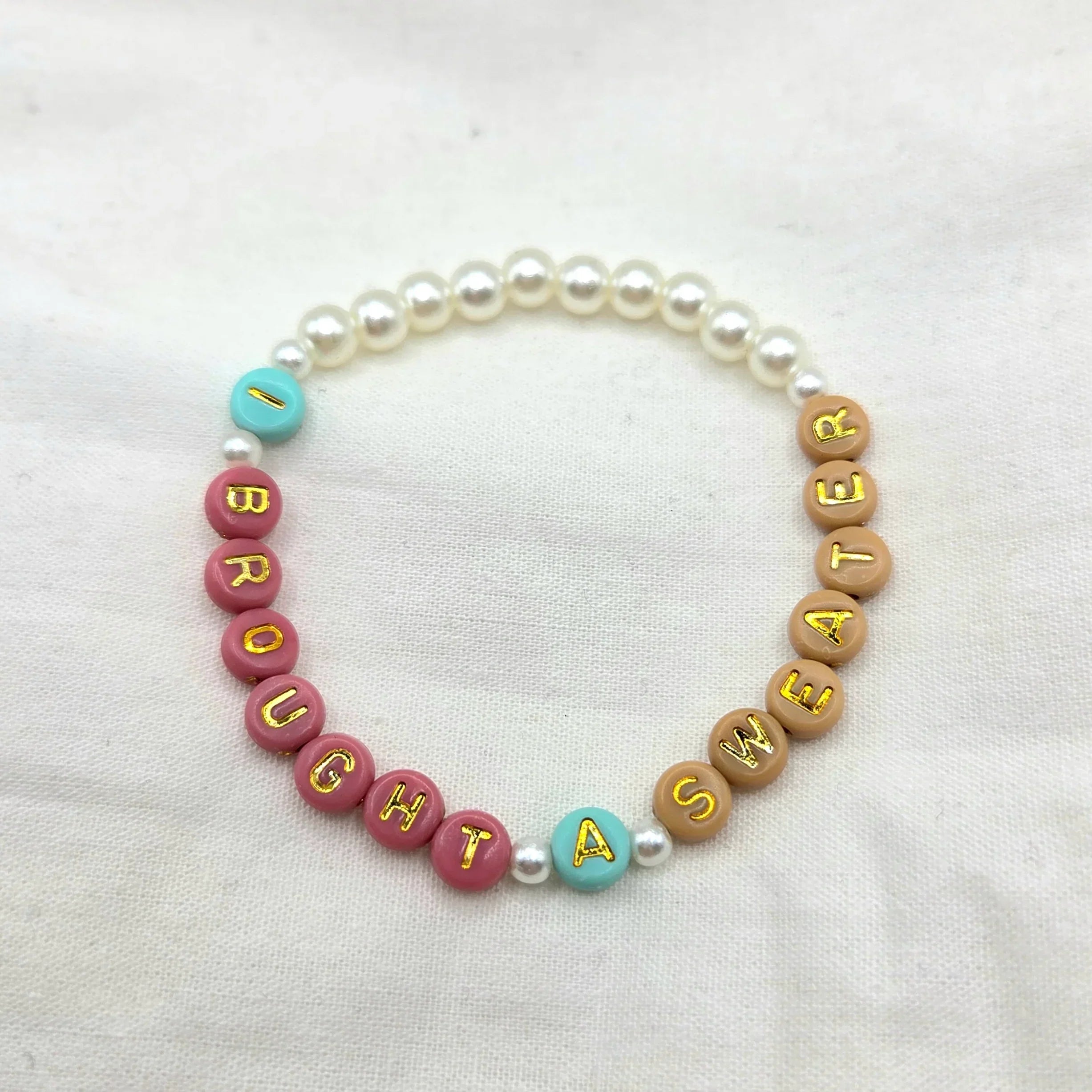 I bought a sweater beaded bracelet with colorful letter beads and pearls on white fabric