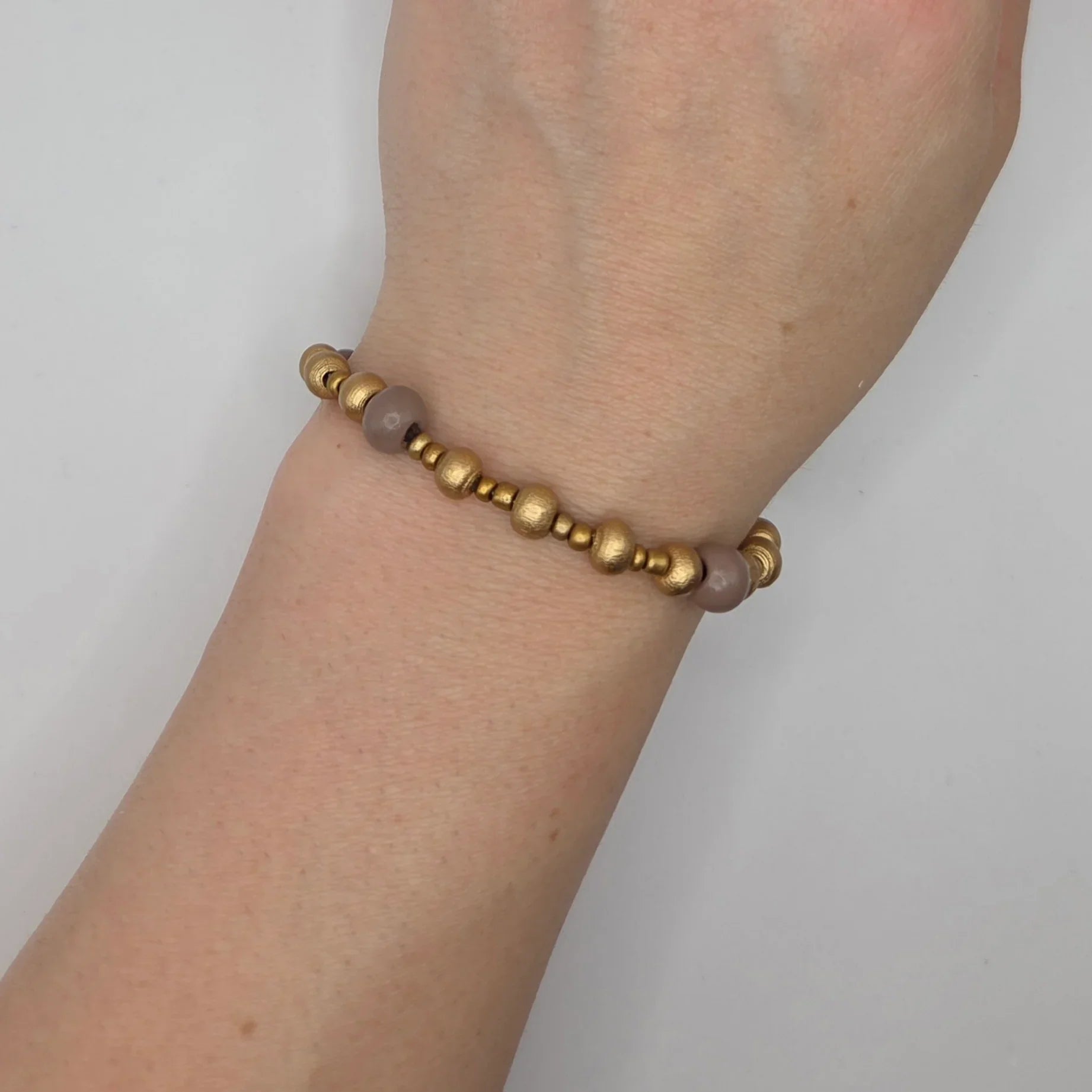 Gold and mauve beaded bracelet on wrist, handmade boho accessory for everyday wear