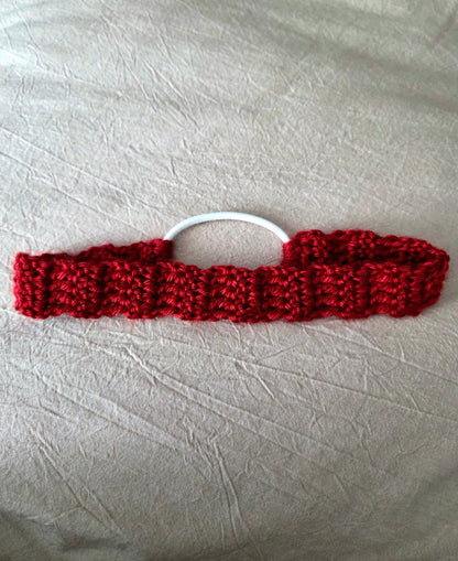 Handmade red crochet hair tie with white elastic on light fabric background