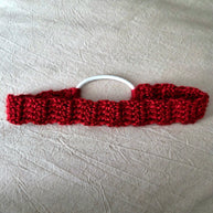 Handmade red crochet hair tie with white elastic on light fabric background