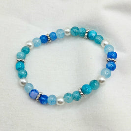 Blue and white beaded bracelet with silver accents on soft fabric background