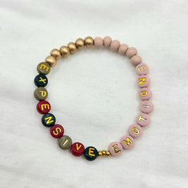Handmade beaded bracelet with 'EXPENSIVE EMOTIONS' in colorful letters, gold accents, soft pink beads