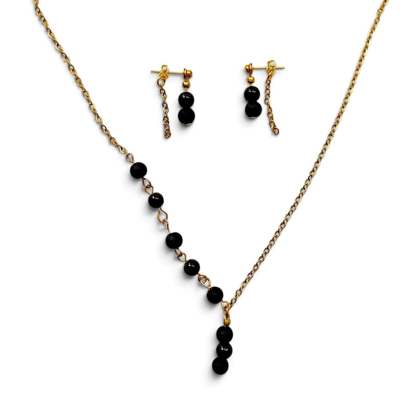 Gold-tone necklace and matching drop earrings with black beads, displayed on a clean white background.