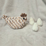 Handmade crochet chicken with eggs, cozy amigurumi toy on soft blanket