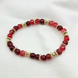 Red and gold beaded bracelet on white fabric background