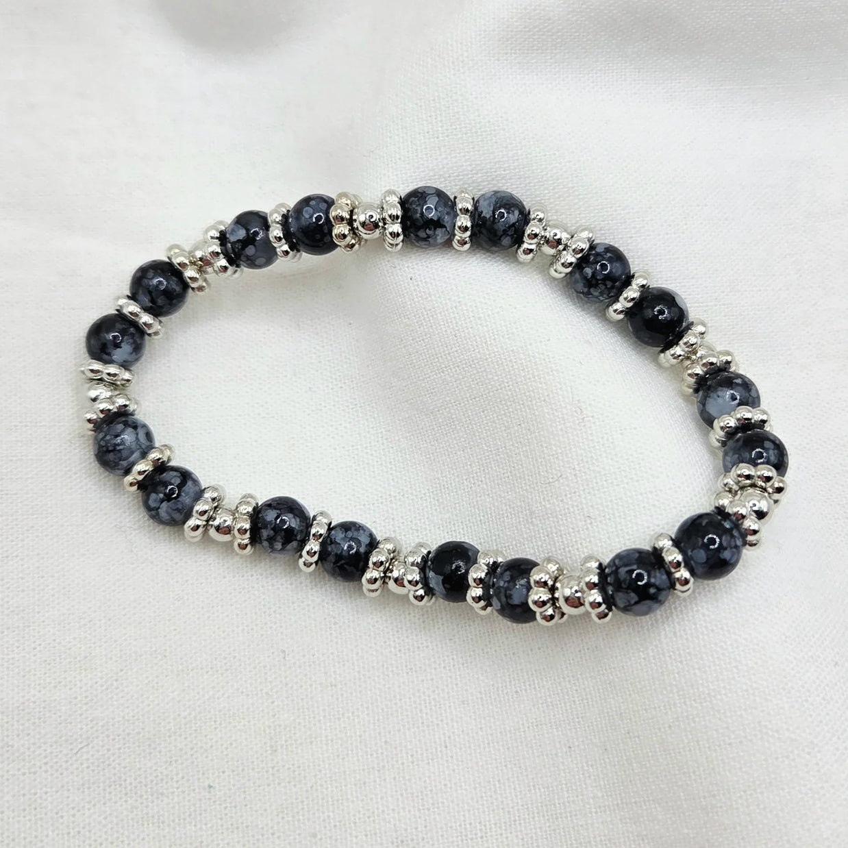 Black and silver beaded stretch bracelet on white fabric background