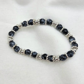 Black and silver beaded stretch bracelet on white fabric background