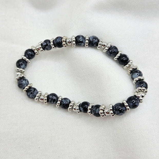 Black and silver beaded stretch bracelet on white fabric background