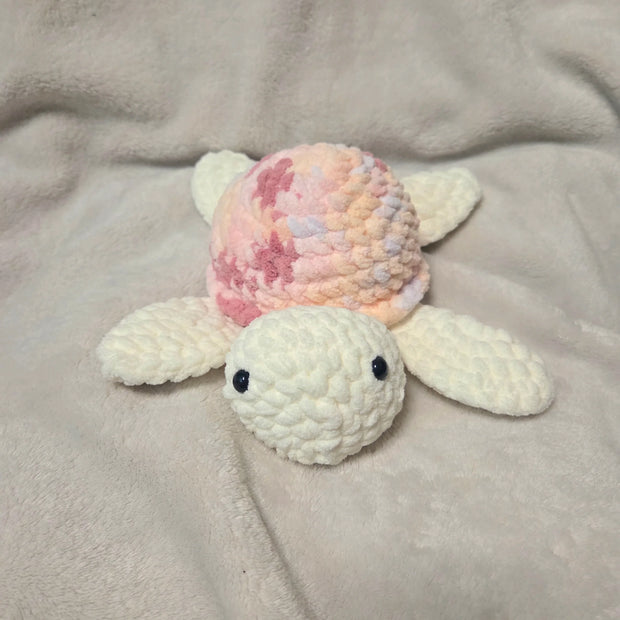 Handmade crochet turtle with pastel shell, cozy and cute amigurumi toy on soft blanket