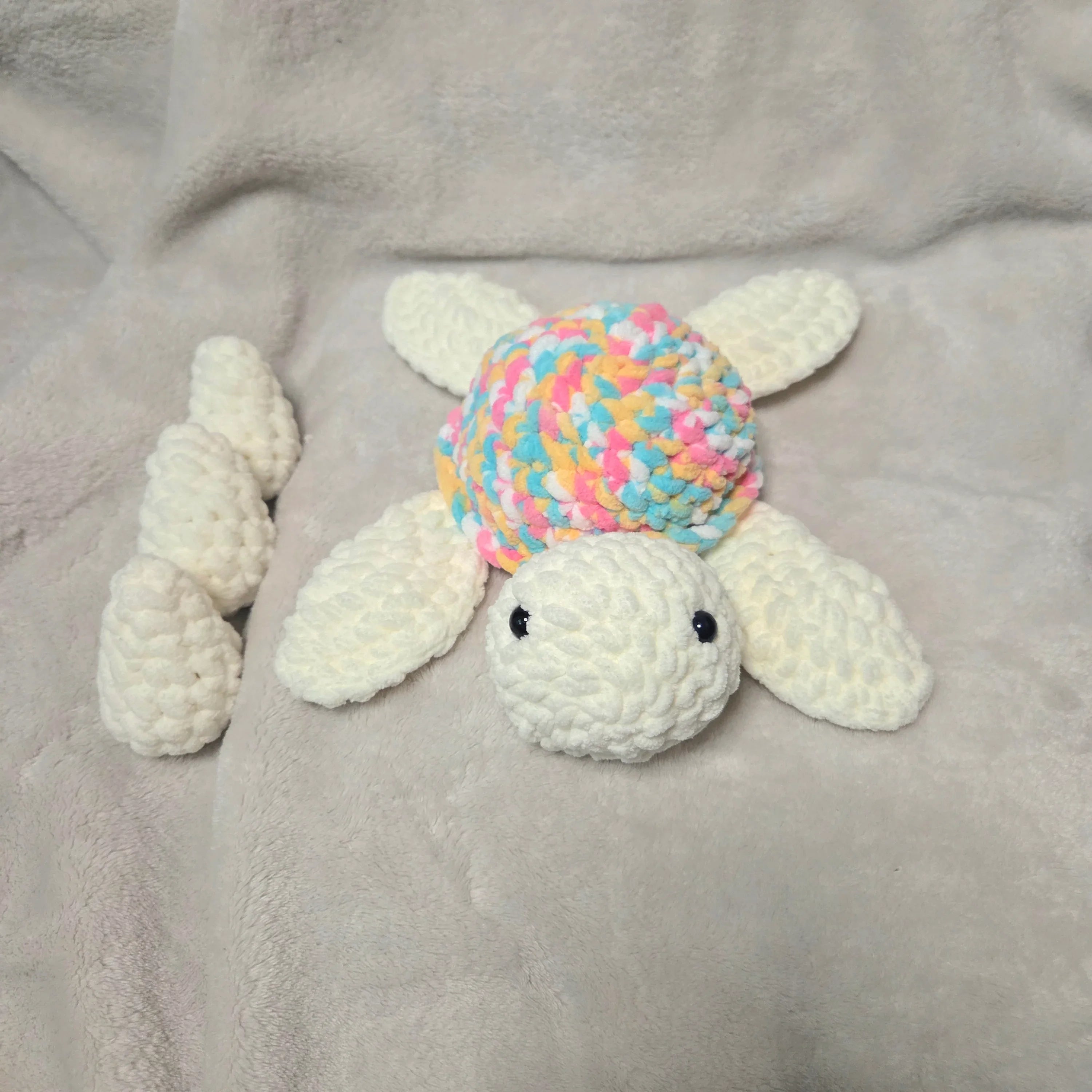Handmade crochet turtle with colorful shell on soft blanket