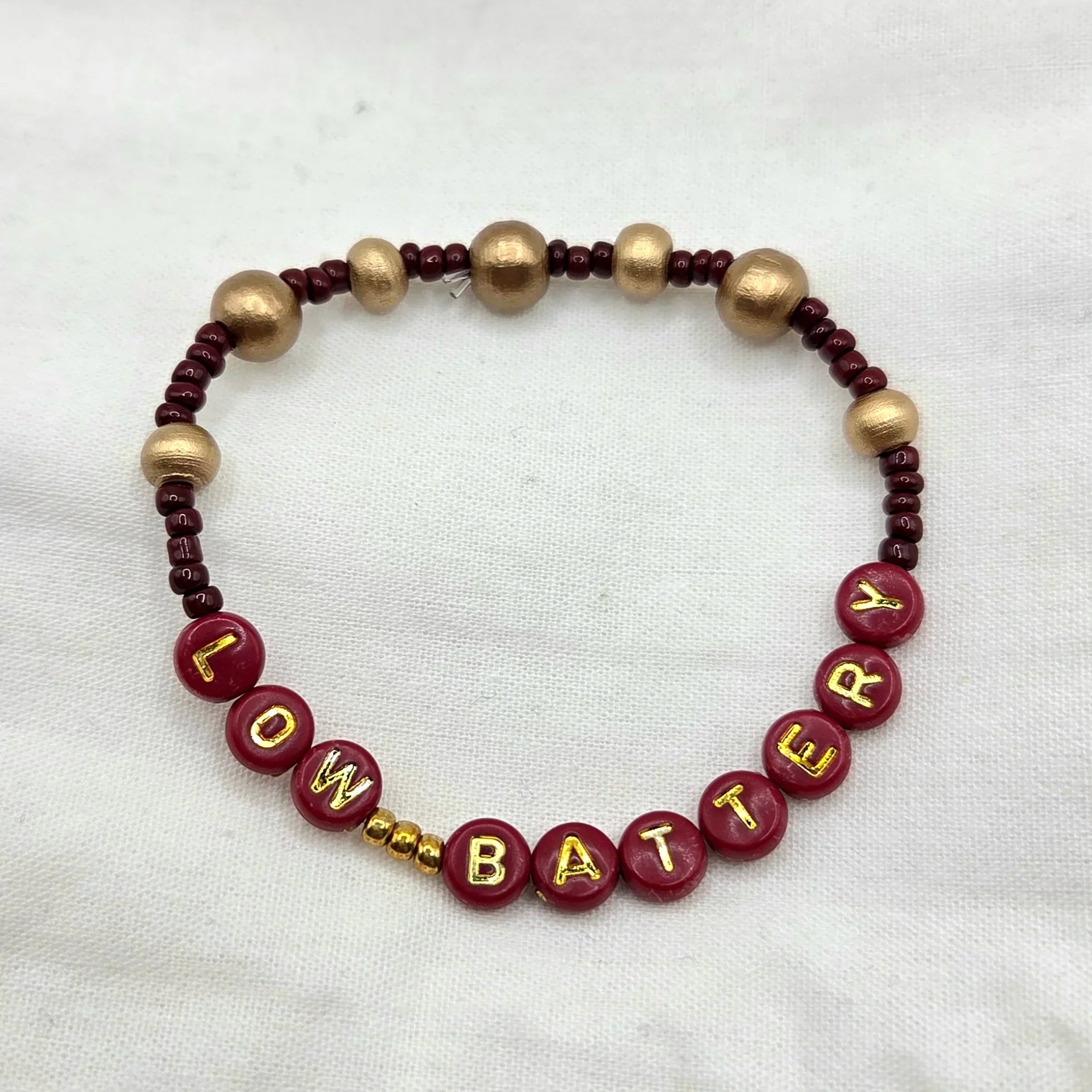 Handmade 'LOW BATTERY' beaded bracelet with burgundy and gold beads, cozy gift for creative souls
