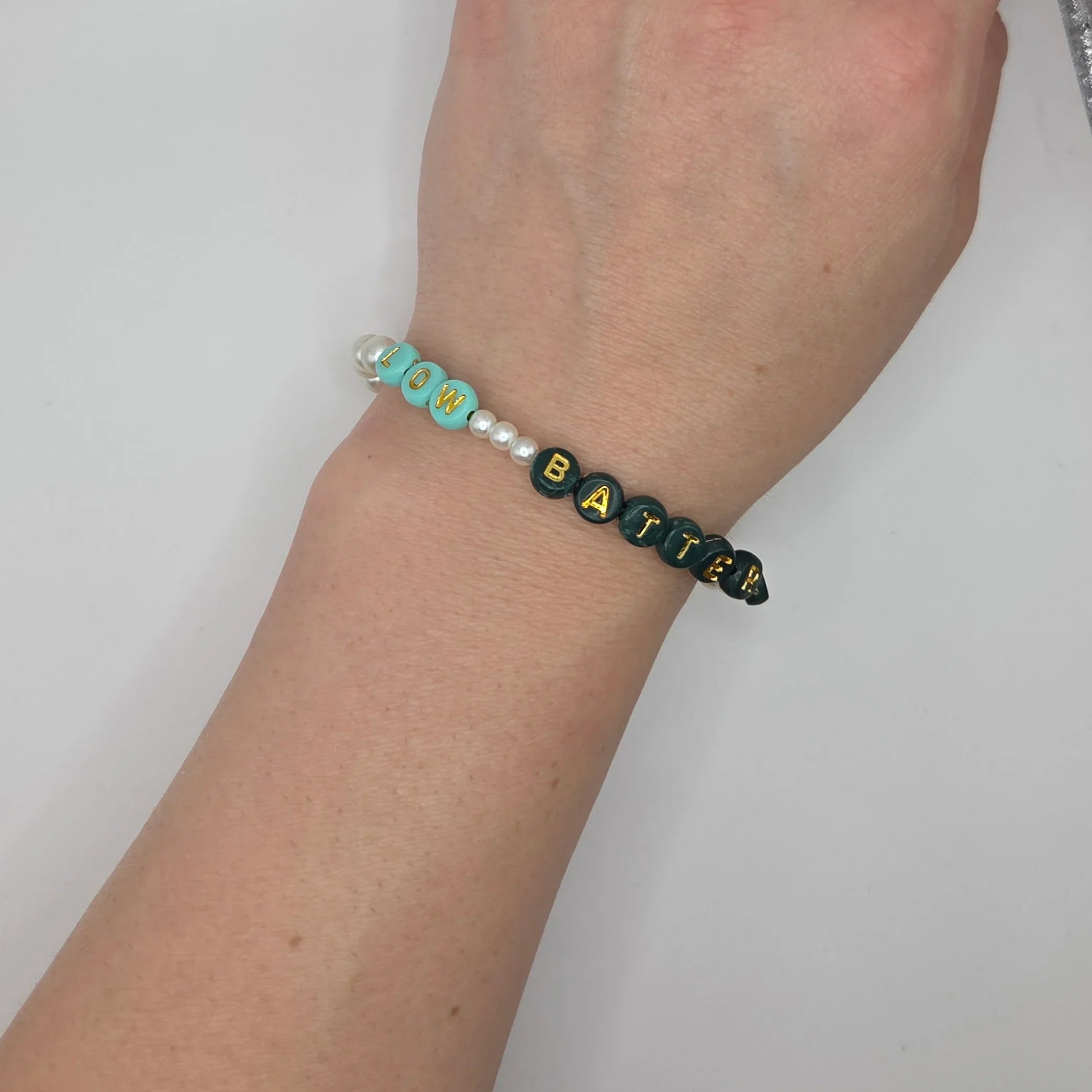 Low Battery beaded bracelet with mint, black, and pearl beads on wrist