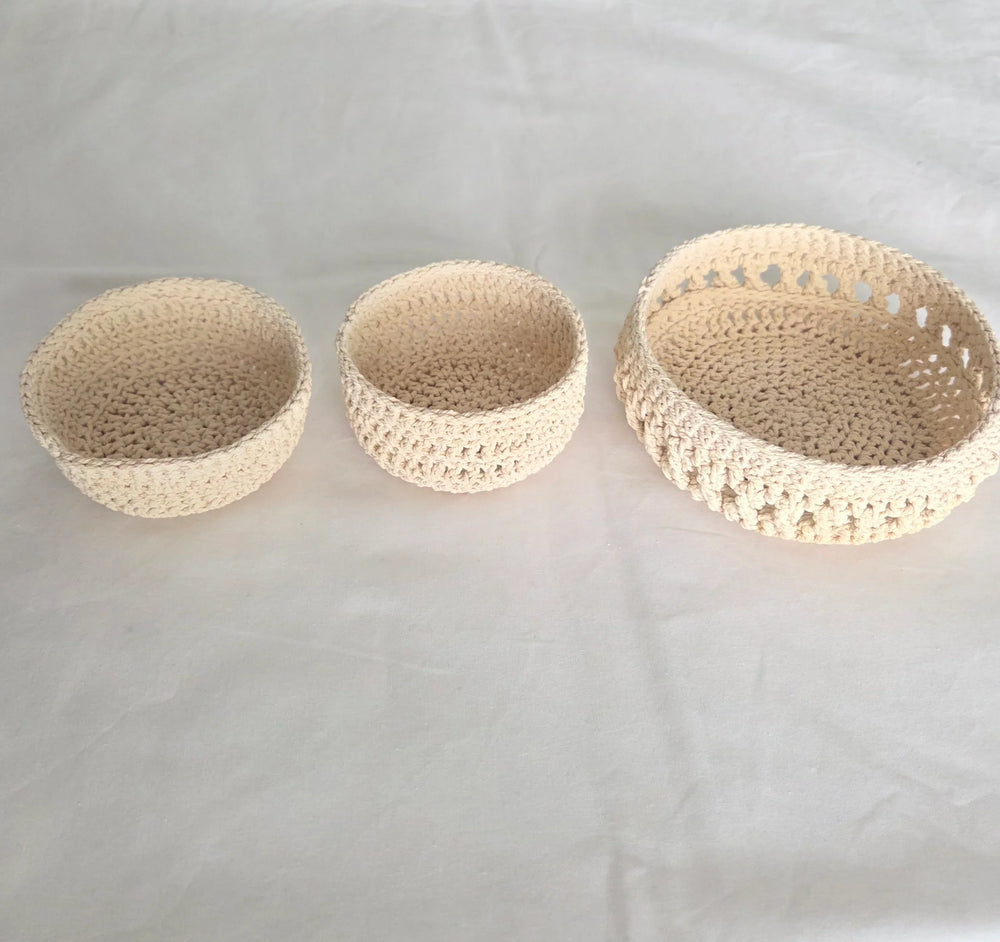 Set of three handmade crochet bowls in neutral tones, perfect for cozy home decor or gifting.