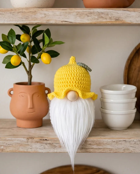 Crochet lemon gnome with white beard, cozy home decor on wooden shelf with potted lemon tree