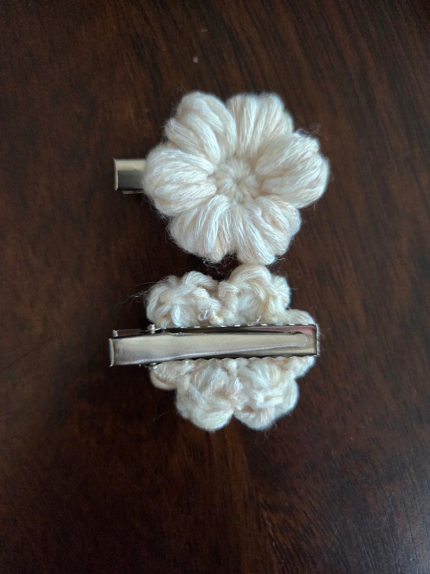 Beige crochet flower hair clips on dark wood surface