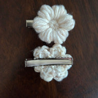 Beige crochet flower hair clips on dark wood surface