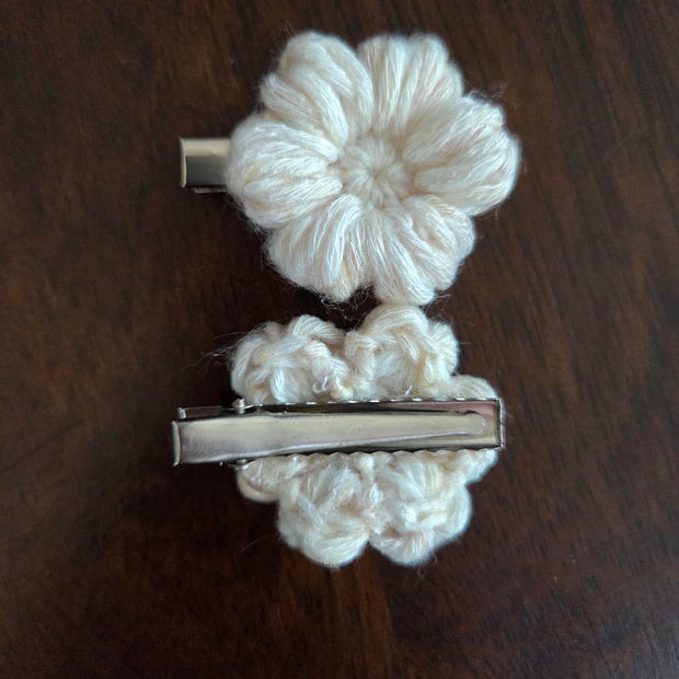 Beige crochet flower hair clips on dark wood surface