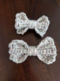 Two handmade crochet bows in light yarn on a dark wooden surface