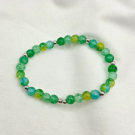 Green and blue marbled bead bracelet with silver accents on white fabric