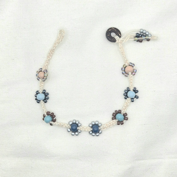Handmade crochet necklace with blue and beige flower beads, macrame cord, and wooden toggle clasp
