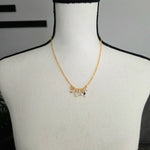 Delicate gold chain necklace with pearl and bead charms, displayed on a mannequin.