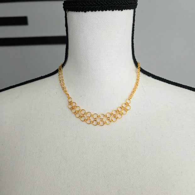Gold chainmaille necklace with interlocking rings displayed on mannequin, handmade jewelry for everyday wear