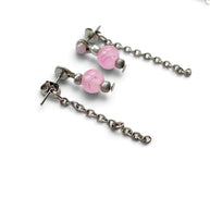 Silver-toned dangle earrings with pink marbled beads and matching chain links, shown on a white background with part of a silver necklace visible at the top.