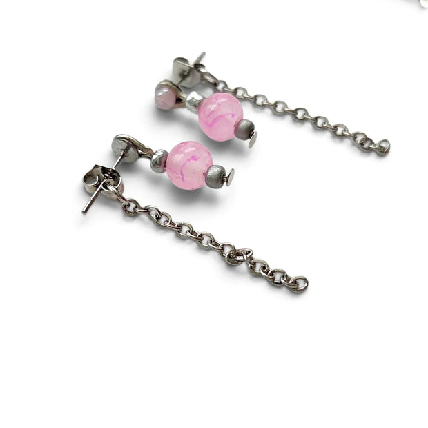 Silver-toned dangle earrings with pink marbled beads and matching chain links, shown on a white background with part of a silver necklace visible at the top.
